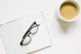 Glasses on notebook with coffee