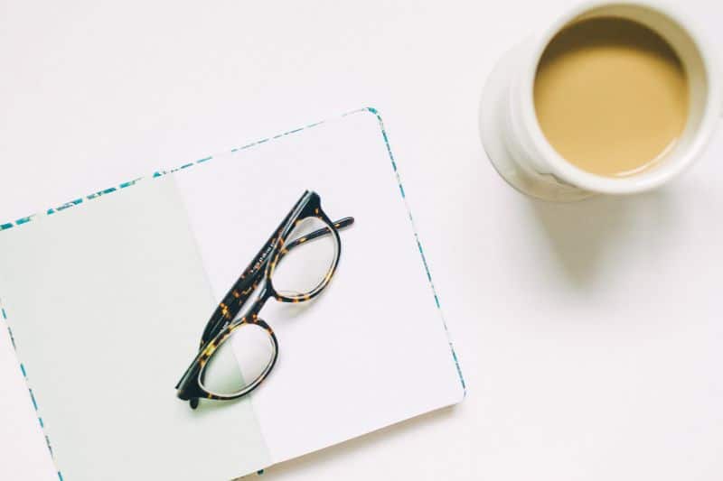 Glasses on notebook with coffee